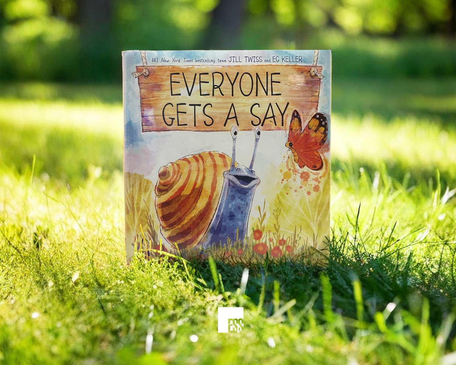 The book 'Everyone Gets A Say' by Jill Twiss and Eg Keller, set in a sunny meadow.